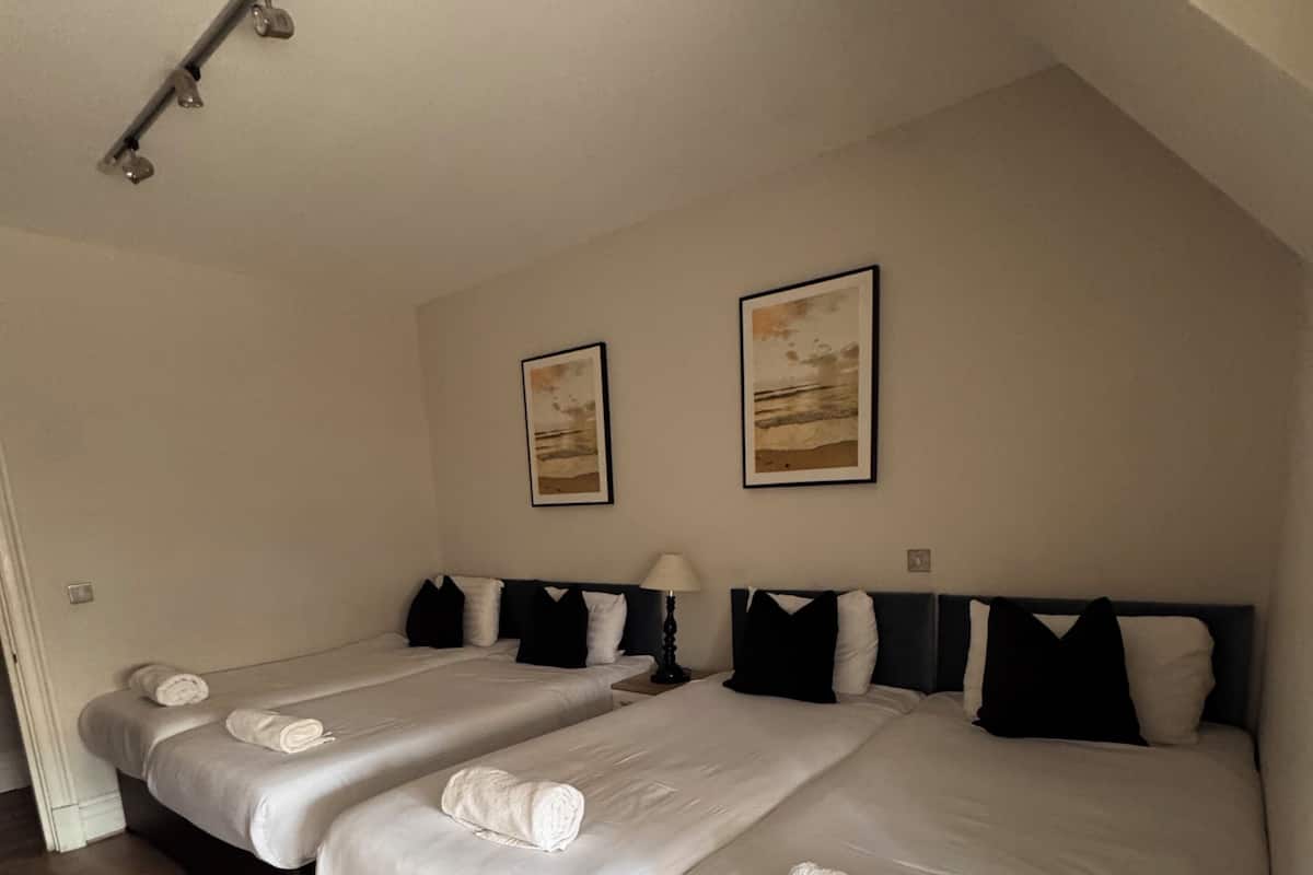 A hotel room with two beds, wooden flooring, and artwork on the walls.