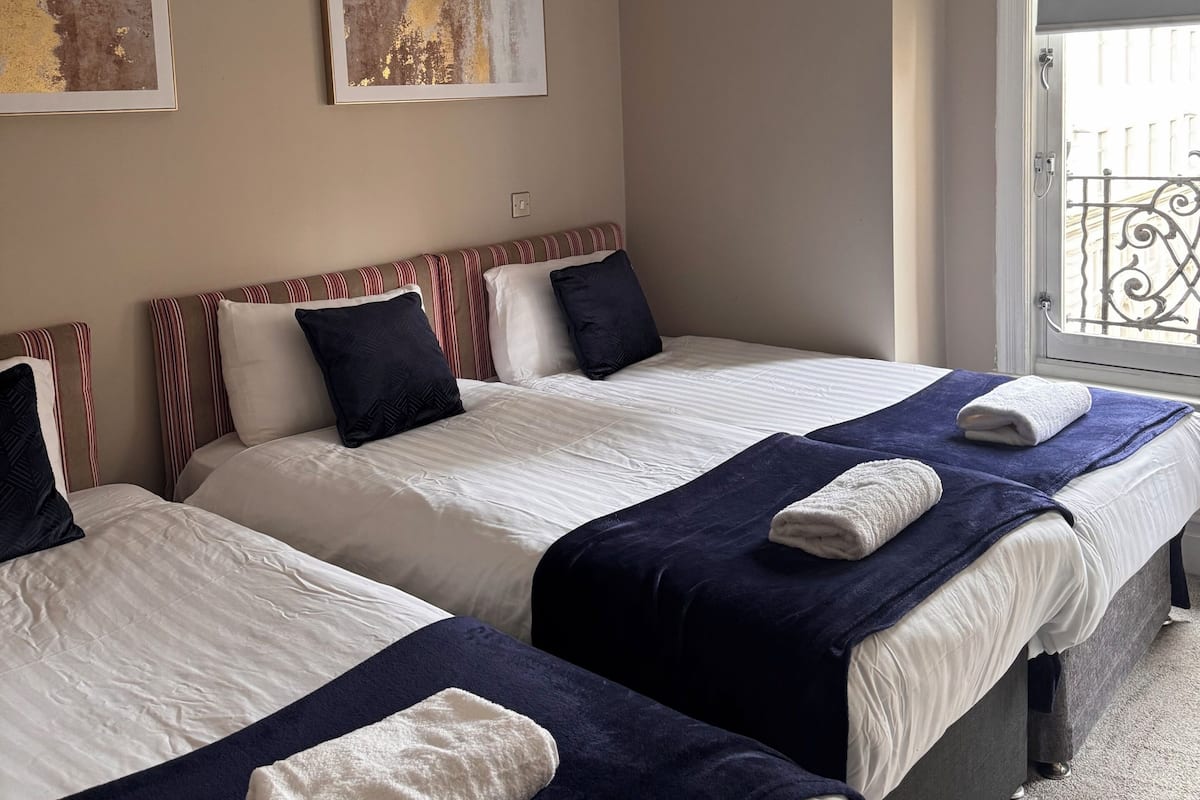 A hotel room with two beds, a window with a view, and artwork on the wall.