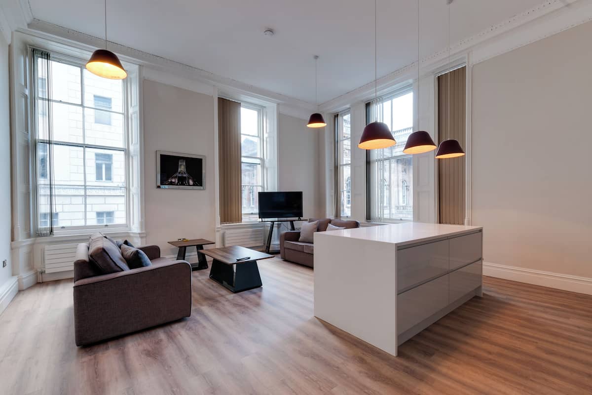 A spacious living area with a sofa, a coffee table, a TV, and pendant lights.