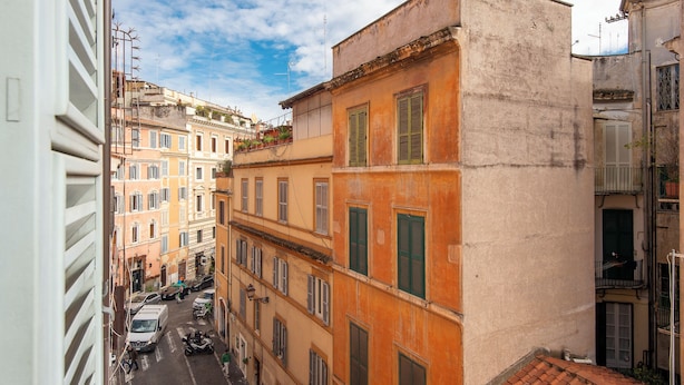 A narrow street with buildings on either side, featuring balconies and a mix of architectural styles. - Panoramic Apartment Fori Imperiali (Rome)