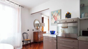 A kitchen with a modern stove, a wooden cabinet, and a blue bowl on the counter. - Panoramic Apartment Fori Imperiali (Rome)