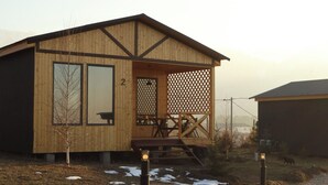 Eine Holzhütte mit Veranda, Hausnummer 2, und einem eingezäunten Bereich.