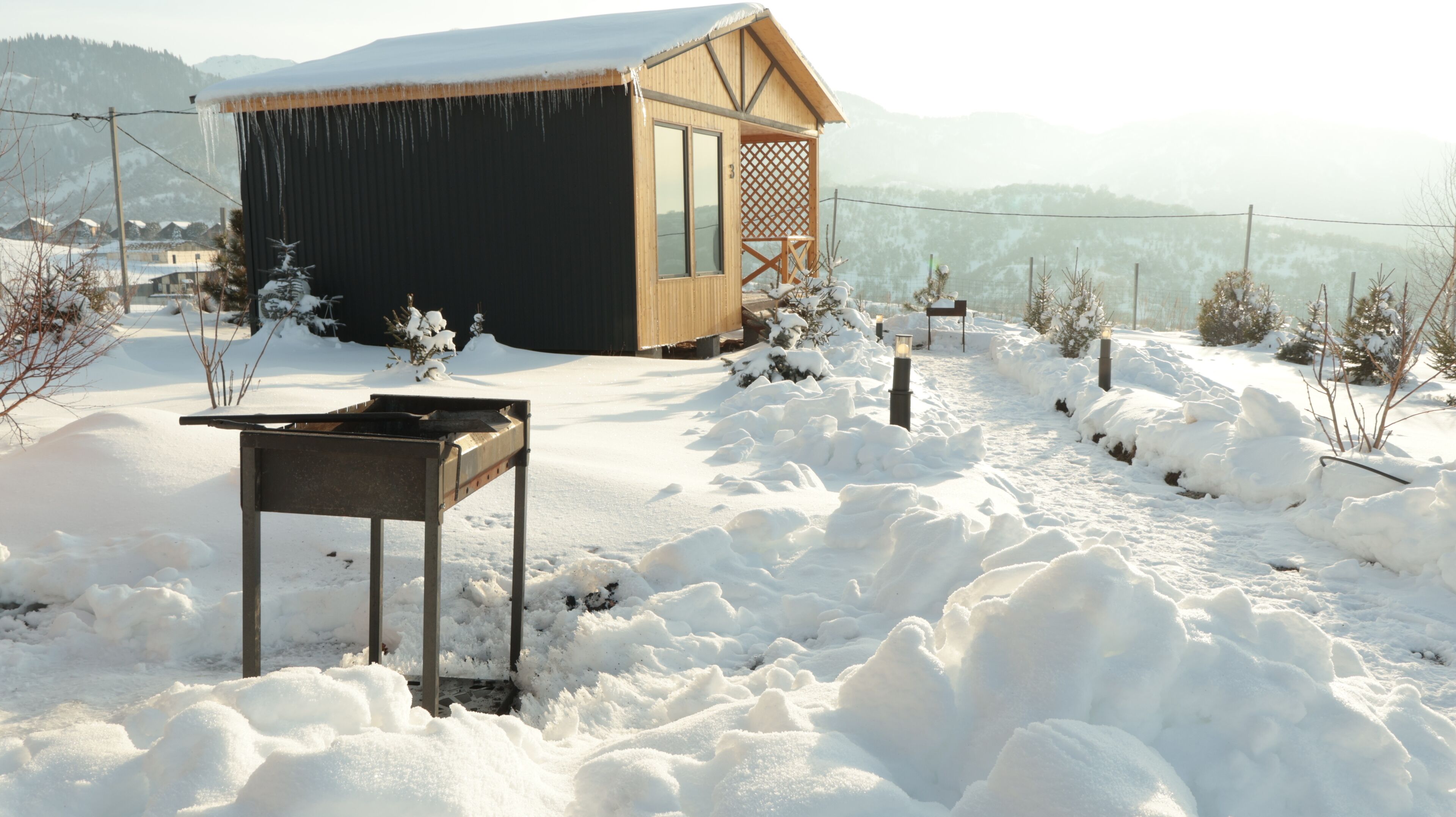 Uma cabana de madeira com uma mesa de metal em uma paisagem coberta de neve.