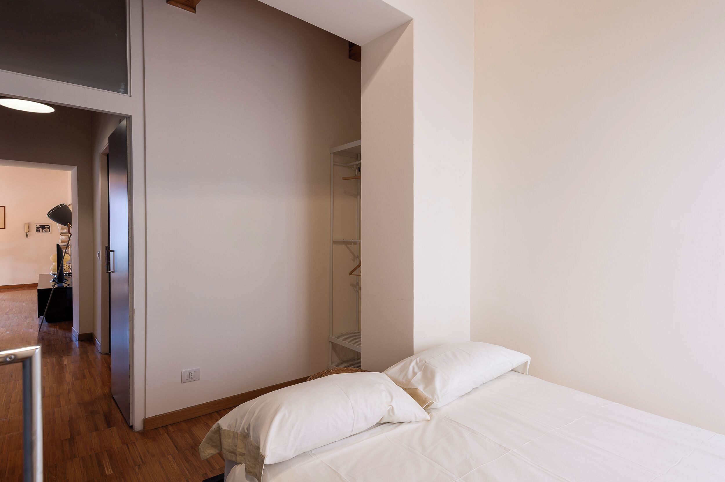 A bedroom with a bed, a wardrobe, and a mirror.
