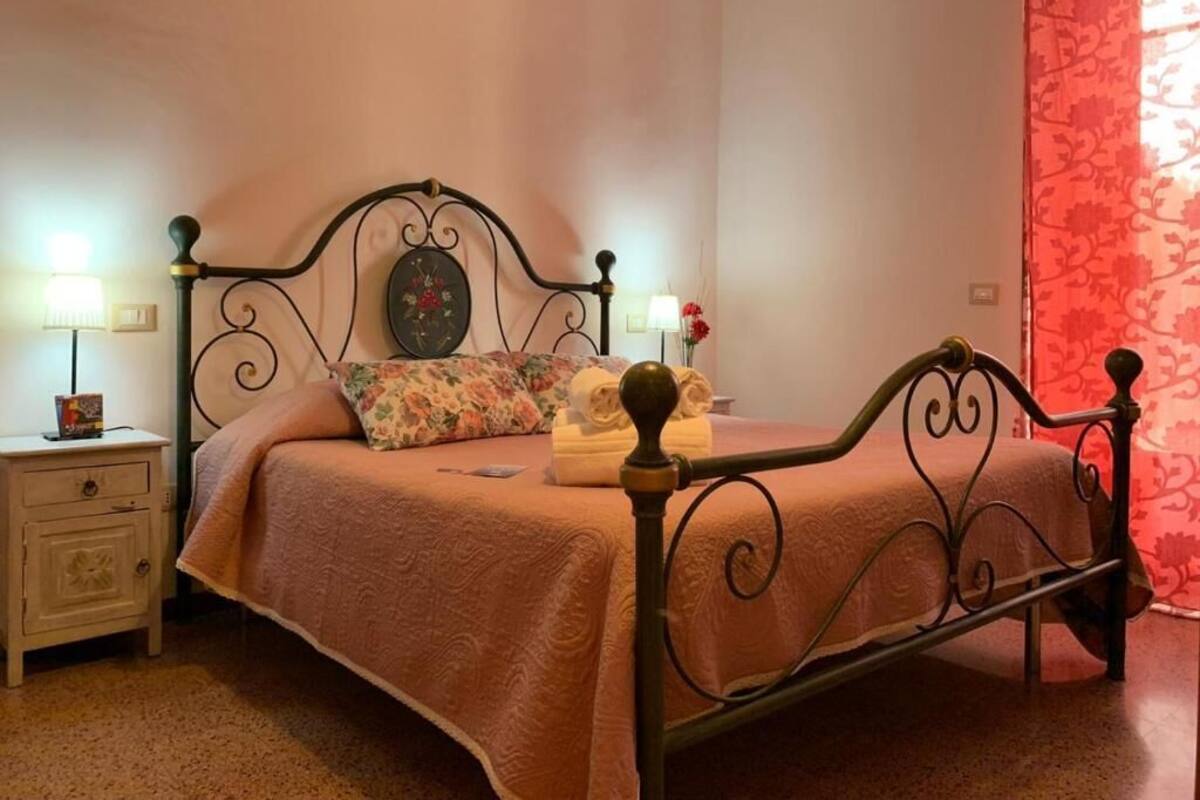 A bed with a metal frame, a bedside table with a lamp, and a floral-patterned pillow.