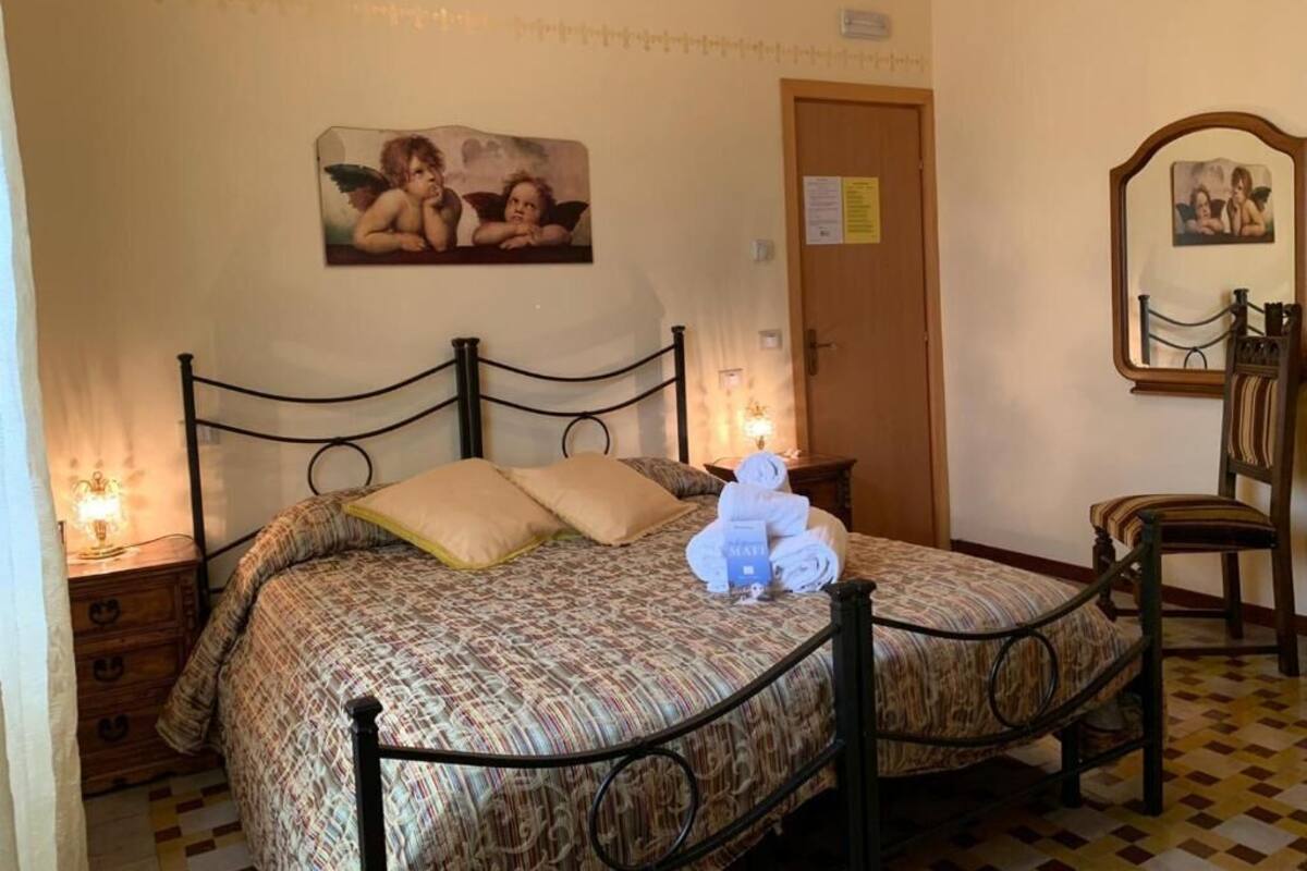 A bedroom with a bed, a wooden dresser, a chair, and a mirror.