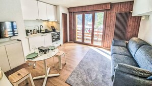 Un espacio habitable compacto con kitchenette, comedor y zona de estar con vistas al exterior.