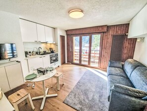 A compact living space with a kitchenette, a dining area, and a seating area with a view of the outdoors. - Lovely apartment for 2 people with WIFI, TV, balcony and pets allowed (Ovronnaz)