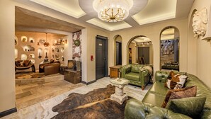 A spacious lobby with a chandelier, leather sofas, a bullhide rug, and a display of decorative items. - WM Cappadocia (Nevşehir)