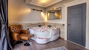 A bathroom with a large bathtub, a leather armchair, and a mirror on the wall. - WM Cappadocia (Nevşehir)