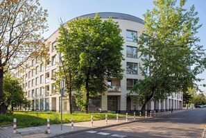 Ein modernes Gebäude mit einer geschwungenen Fassade, umgeben von Bäumen und einem Bürgersteig.