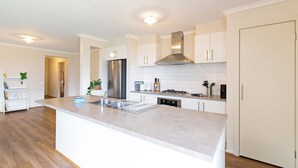 A modern kitchen with a central island, stainless steel appliances, and white cabinetry.