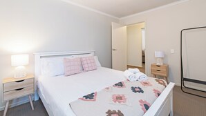 A neatly arranged hotel room with a bed, bedside tables, a lamp, and a mirror.
