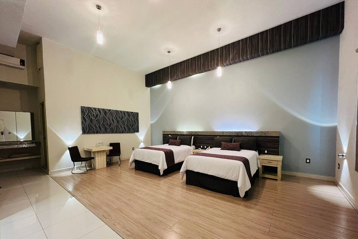 A modern hotel room with two beds, a desk, and a large mirror.