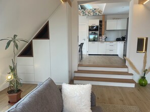 A modern living room with a staircase leading to a kitchen and dining area. - The vineyard setting, the luxurious gite (Wettolsheim)
