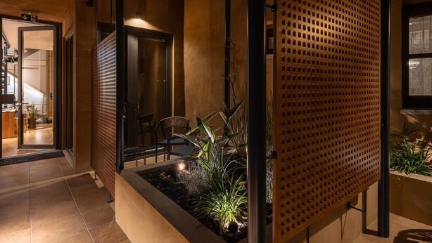 A modern interior with a wooden partition, a seating area with chairs, and a small garden with plants. - Santa Clara Hotel (Chania)