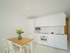 A modern kitchen with white cabinetry, a wooden dining table, and a vase with flowers. - CHL Naos del Mar, lovely place pool beach (Los Llanos de Aridane)