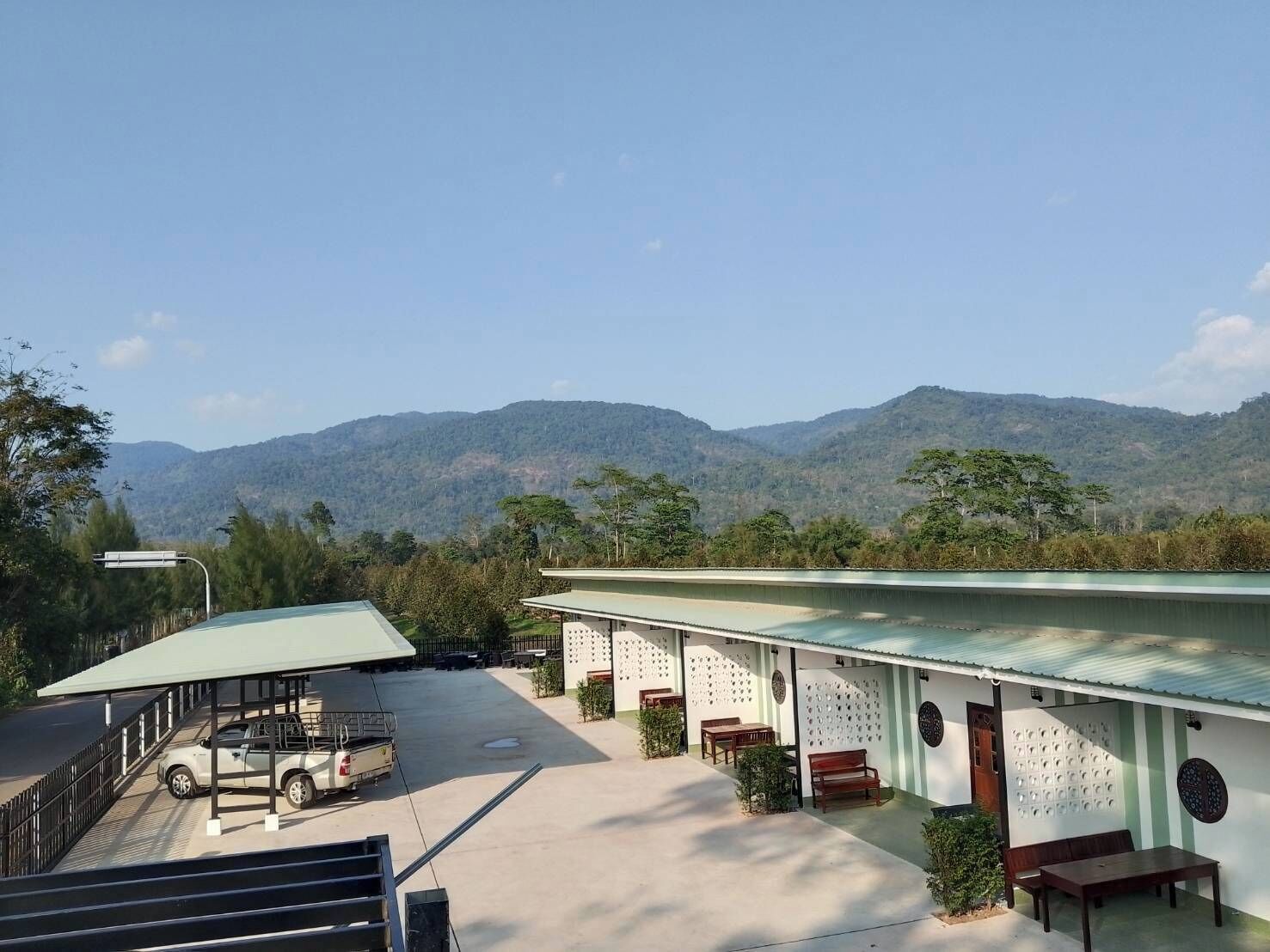 A hotel with a covered parking area, outdoor seating, and a view of mountains.