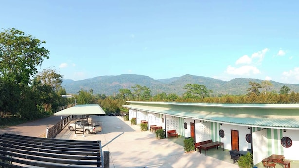 A building with a covered outdoor area, a car parked inside, and a view of mountains in the background.