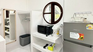 A compact kitchenette with a microwave, a small refrigerator, and a sink.