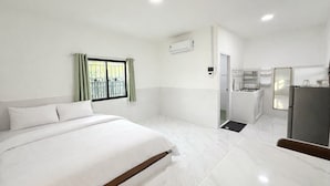 A hotel room with a bed, a small kitchenette, and a bathroom.