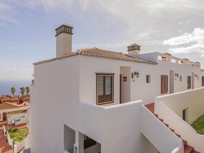 A white building with a tiled roof, a staircase, and a view of the ocean. - CHL Serycam Bre ña Baja, infinity views (Breña Baja)