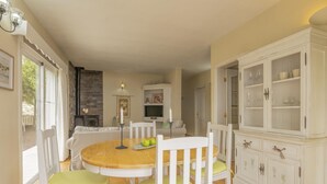 A dining area with a round wooden table, white chairs, and a cabinet with glass doors. - CHL La Concepción, Adeje: amazing sea views (Adeje)