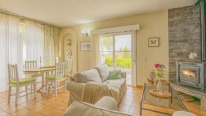 A cozy living room with a fireplace, a dining area with chairs, and a view of greenery outside. - CHL La Concepción, Adeje: amazing sea views (Adeje)