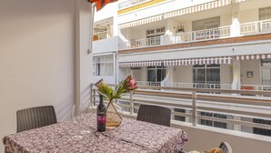 A balcony with a table set for two, a bottle of wine, and a vase with flowers. - CHL El Faro, next to the Puerto Naos beach (Puerto Naos, Los Llanos de Aridane)