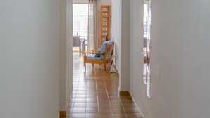 A hallway with a wooden chair and a table, leading to a balcony with a view. - CHL El Faro, next to the Puerto Naos beach (Puerto Naos, Los Llanos de Aridane)