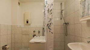 Un bany amb vàter, un lavabo, dutxa i barra de tovalloles.