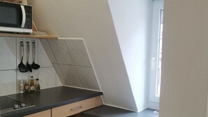 Una cuina petita amb microones, fogó i armaris de fusta.