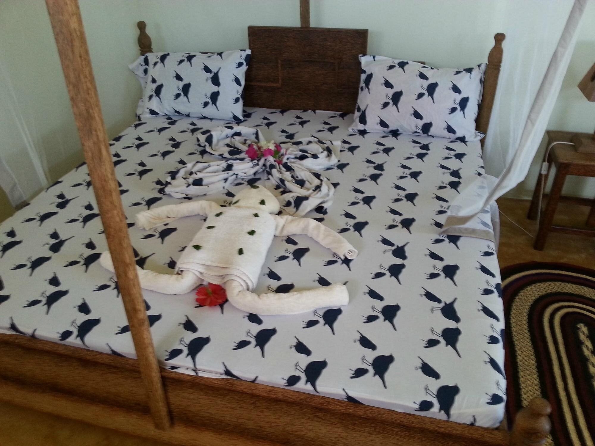 Una cama con dosel, ropa de cama estampada y un adorno con forma de pájaro.
