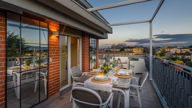 A rooftop terrace with tables set for dining, overlooking a cityscape. - The Sunwall Loft in Lucca (Lucca)