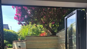 A patio area with a green chair, a small table, and a potted plant. - Chorlton Garden Rooms - Relax, work, stay & play. (Manchester)