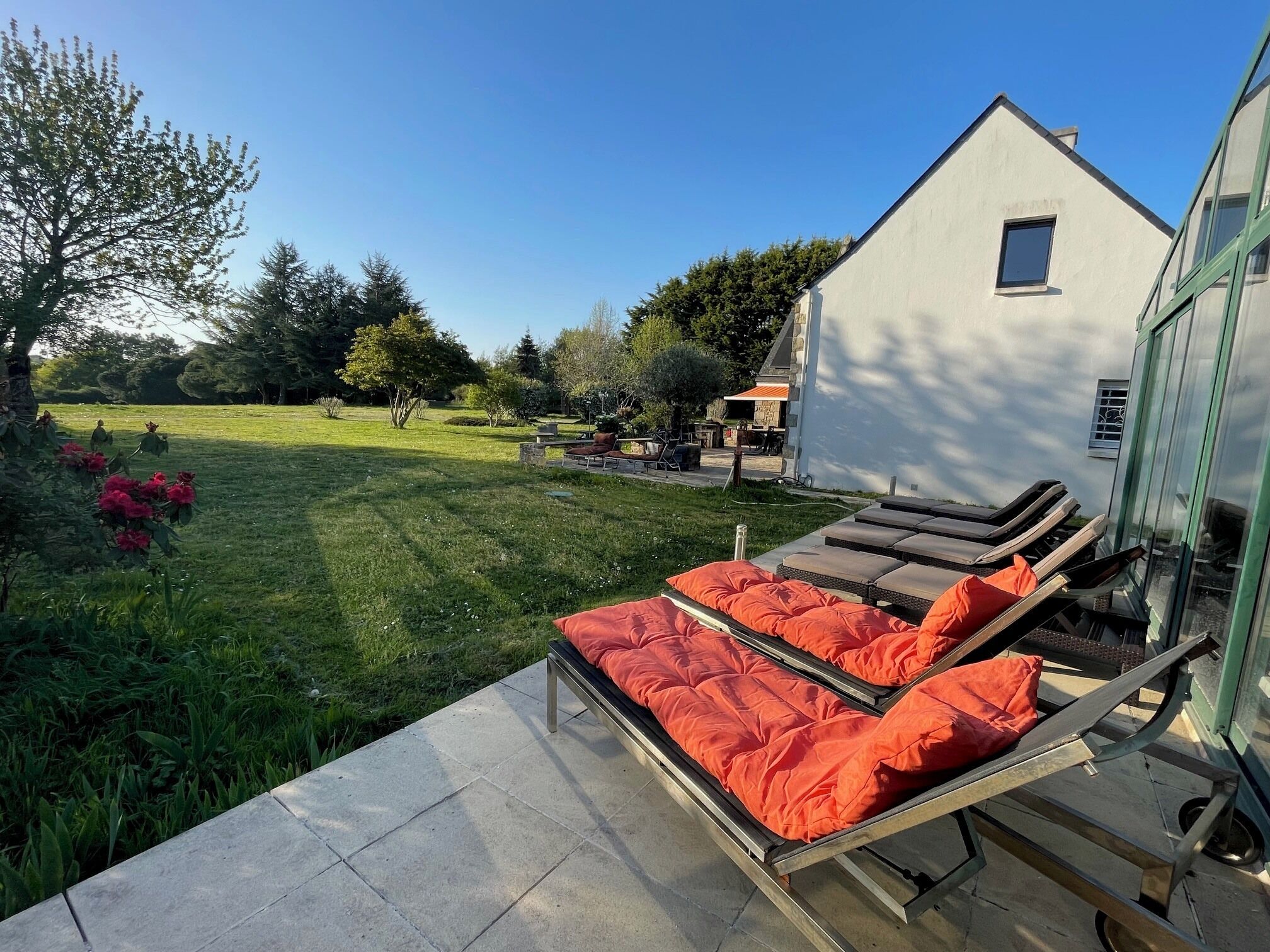 Eine Terrasse mit Liegestühlen und ein weißes Gebäude im Hintergrund.