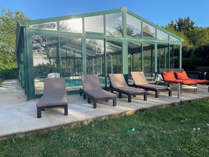 Ein überdachter Außenbereich mit Sitzgelegenheiten, Loungemöbeln und einem Pool.