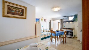 Una habitación acogedora con cama, mesa de comedor y kitchenette.