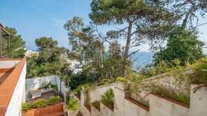 Un jardín en la azotea con jardineras escalonadas y vista al mar.