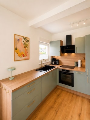 A modern kitchen with a built-in oven, a sink, and a window with blinds. - Holiday Home 'Landhaus Holly' with Private Terrace, Veranda, Wi-Fi and Air Conditioning (Frielendorf)