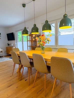 A dining area with a wooden table, six chairs, and hanging pendant lights.