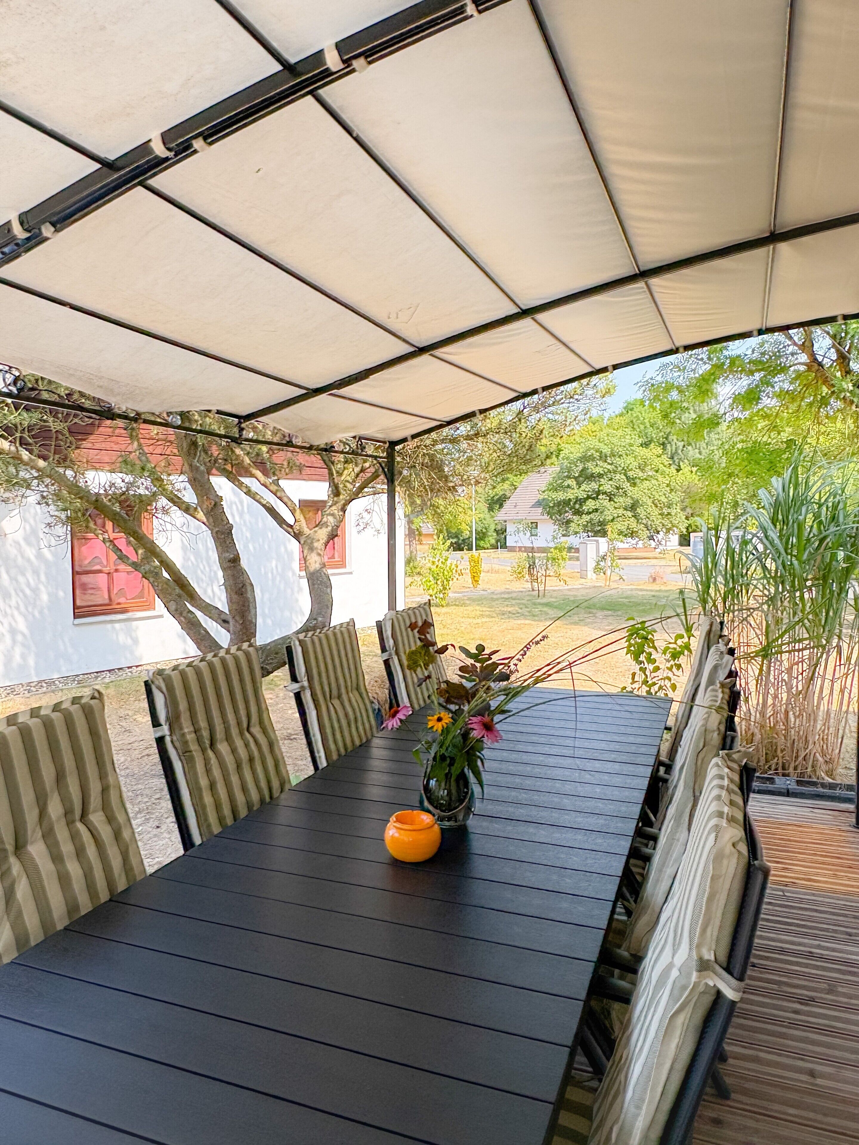 An outdoor dining area with a table, chairs, a canopy, and a view of the surrounding landscape.