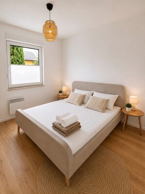A bedroom with a large bed, two bedside tables, a window with a view, and a hanging light fixture. - Holiday Home 'Landhaus Holly' with Private Terrace, Veranda, Wi-Fi and Air Conditioning (Frielendorf)