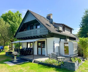 Een huis met twee verdiepingen, een balkon, een overdekte patio en een tuin.