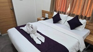A hotel room with two beds, a wooden headboard, a nightstand, a robe, and a curtain. - Hotel Sagar Family Lodge (Man)