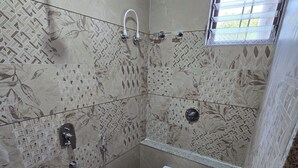 A bathroom with a shower, toilet, and two pink buckets. - Hotel Sagar Family Lodge (Man)