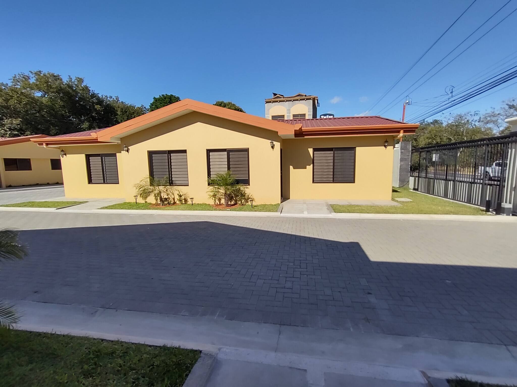 A two-story house with a red roof, a small porch, and a paved driveway.