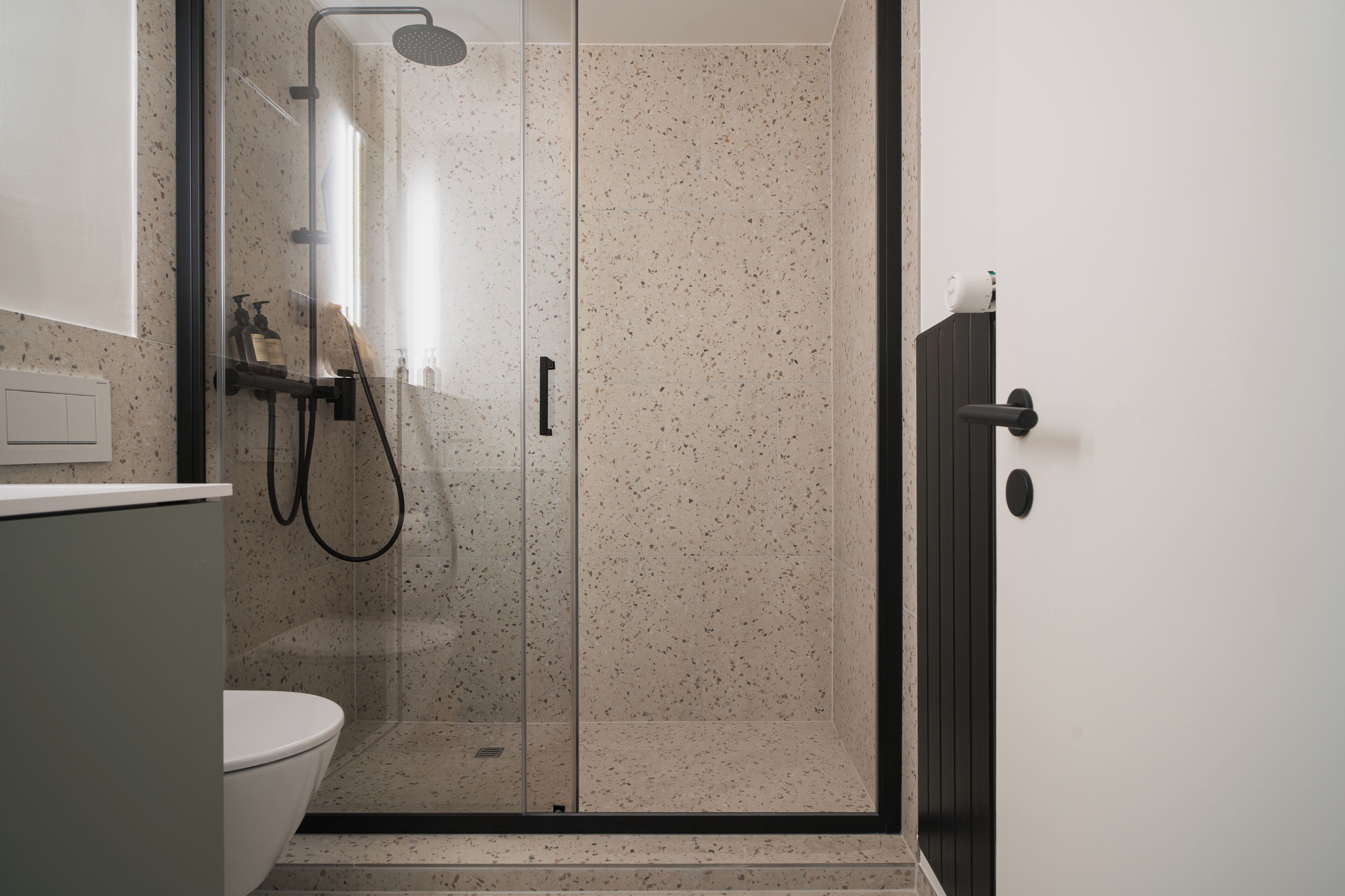A modern bathroom with a glass-enclosed shower, a toilet, and a sink.