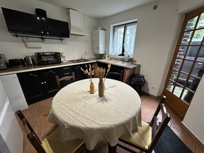 Ett kompakt kök med ett matbord, en inbyggd ugn och ett fönster med gardiner.