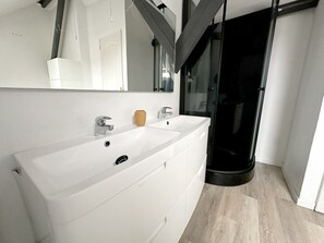 A modern bathroom with a large white sink, two faucets, a mirror, and a glass shower enclosure. - Charming Cottage in a Converted Farmhouse with Wi-Fi (Vendin-le-Vieil)